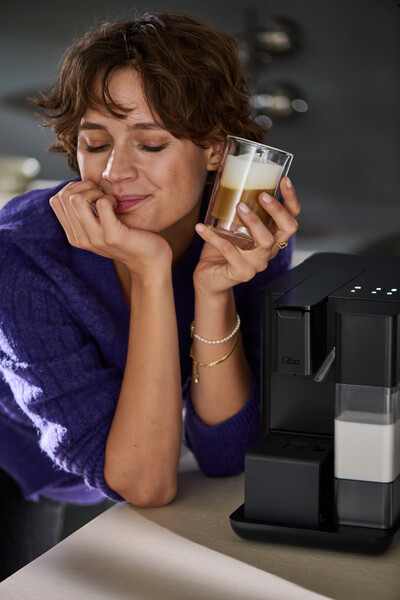 Person trinkt Latte Macchiato an Kaffeemaschine