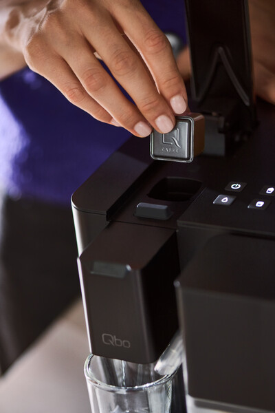 Hand setzt Kaffeekapsel in Maschine ein