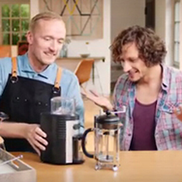 Zwei Personen mit Kaffeemaschinen am Tisch