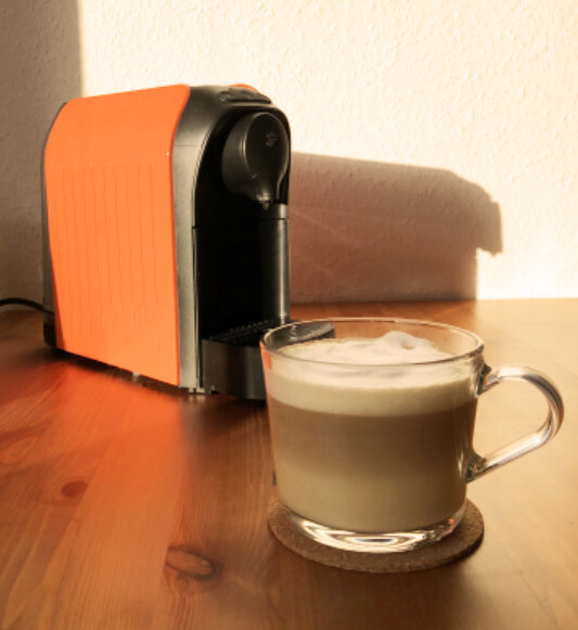 Orange Kaffeemaschine mit Glas Cappuccino