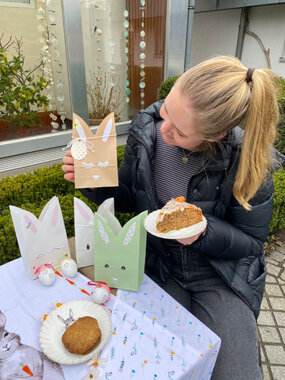 Person mit Ostergebäck und Hasen-Geschenktüten
