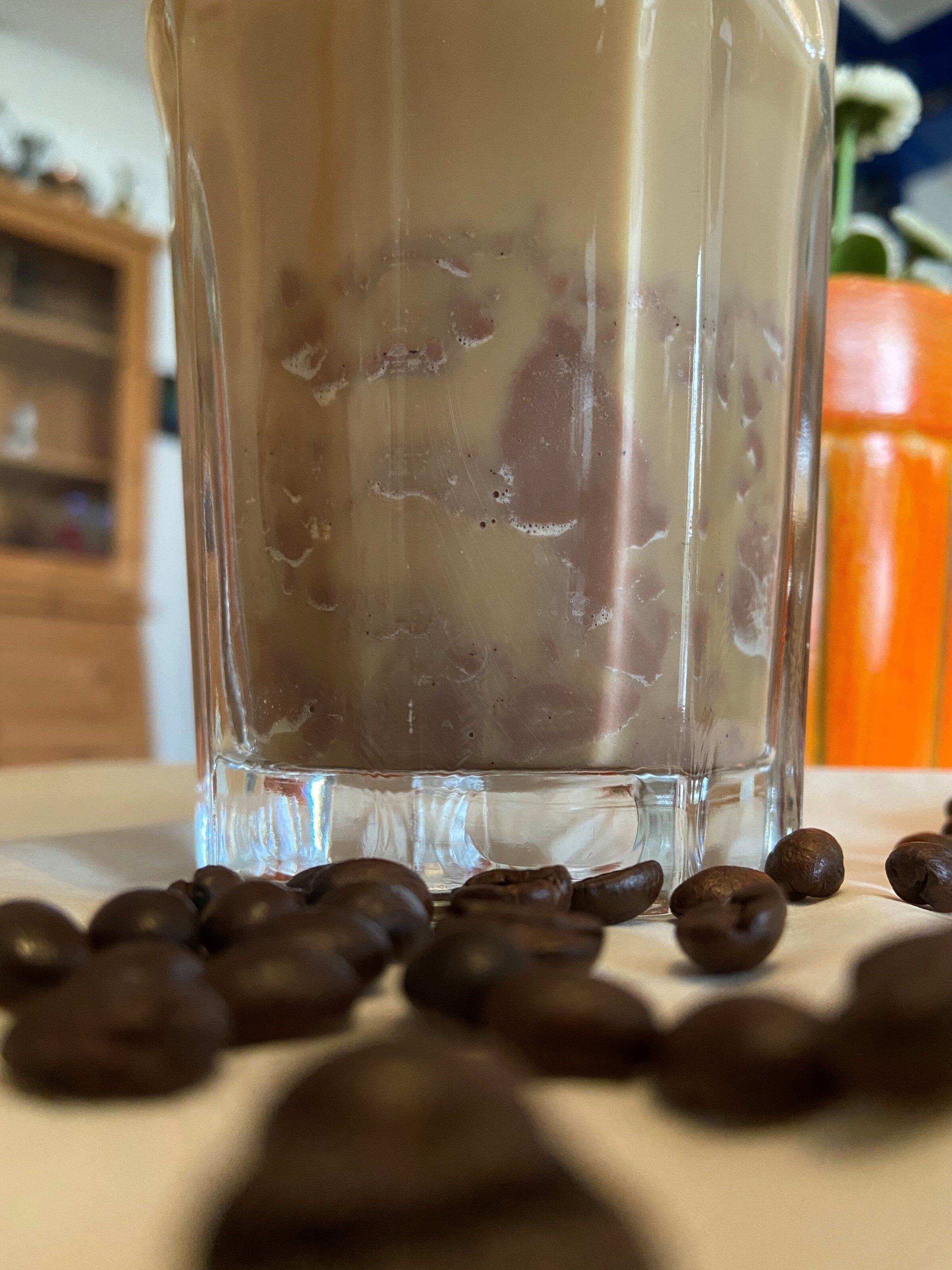 Eiskaffee im Glas mit Kaffeebohnen davor