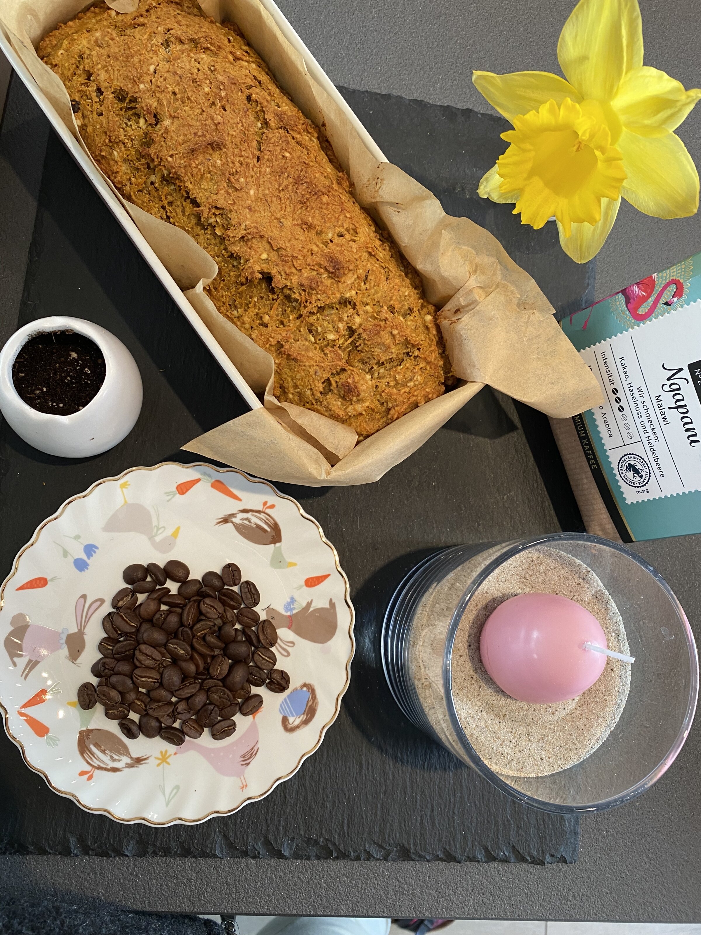 Kuchen, Kaffeebohnen, Osterteller und gelbe Narzisse