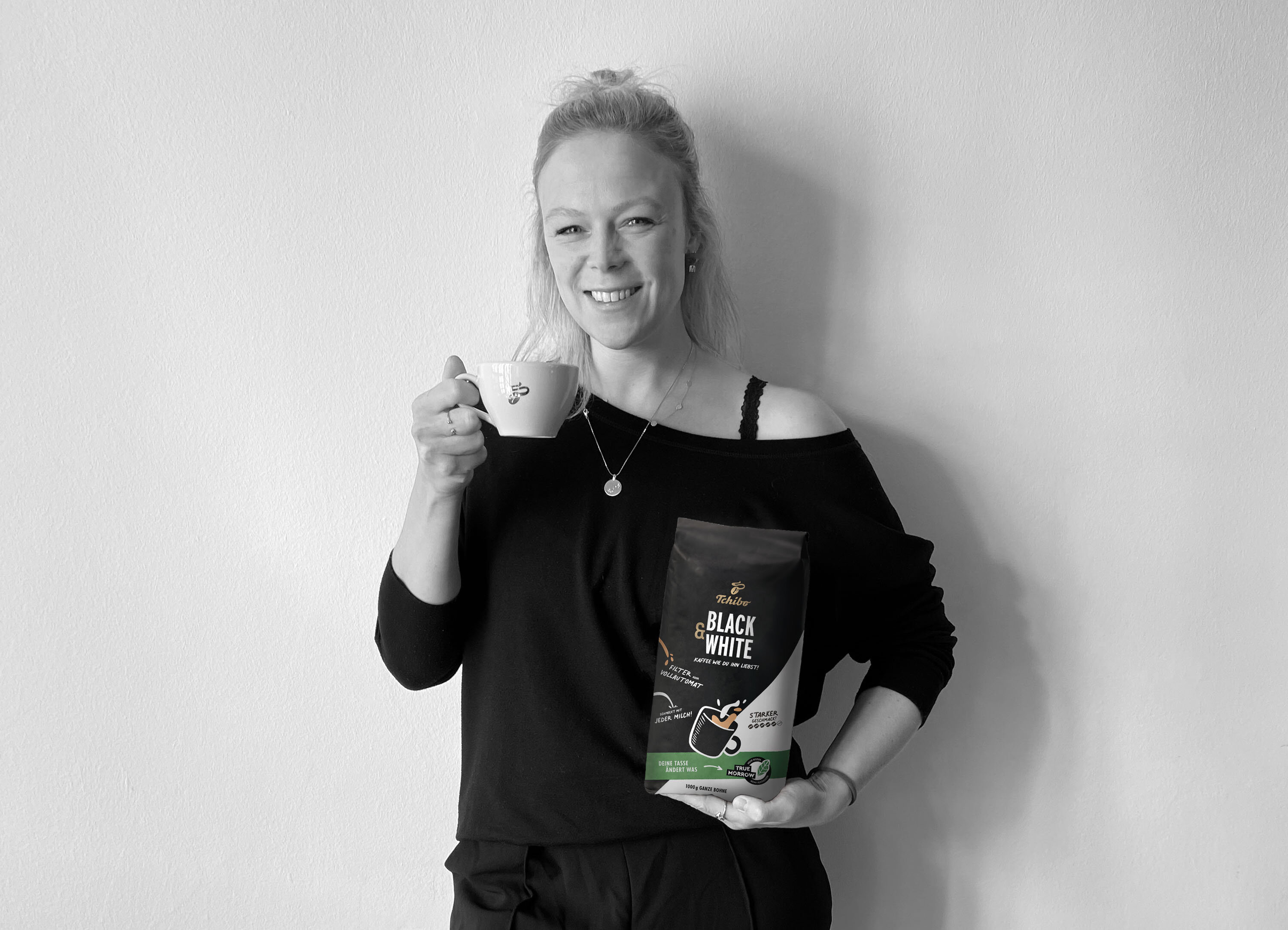 Frau hält Kaffeetasse und Tüte „Black & White“