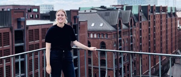 Person auf Balkon vor Hamburger Speicherstadt