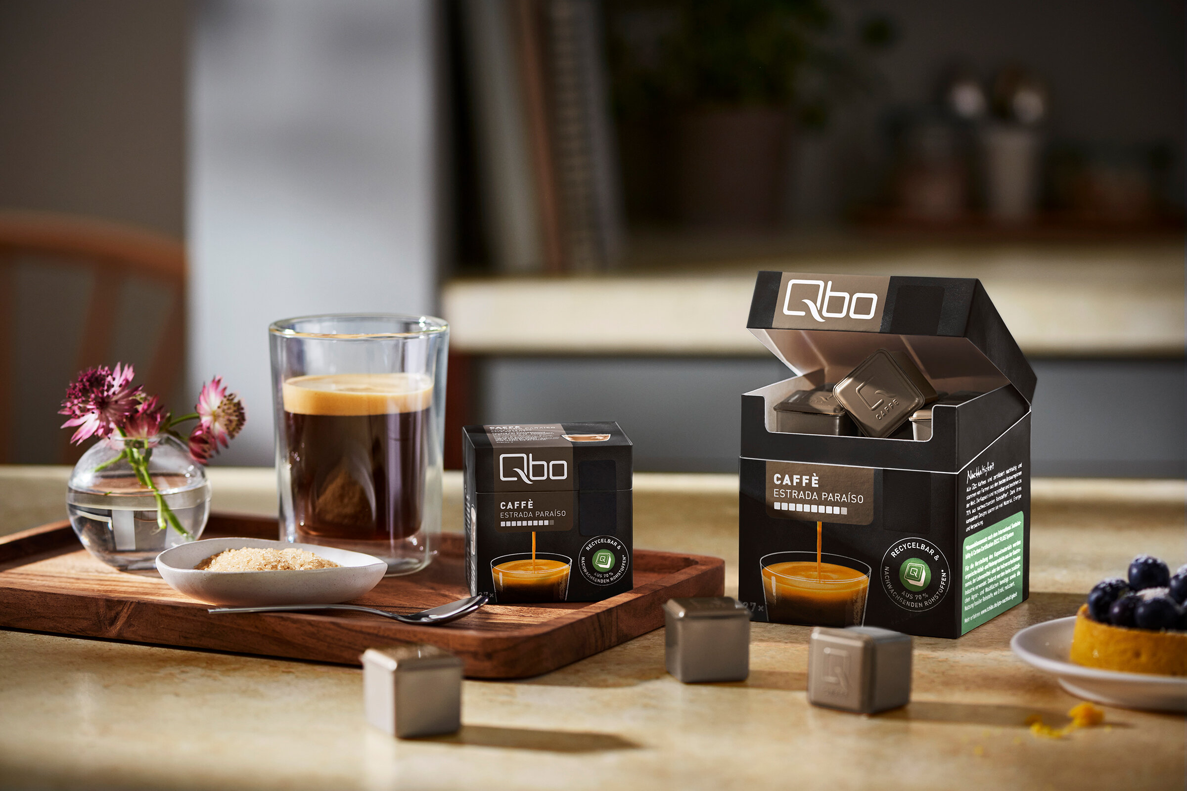 Kaffeeglas mit Qbo-Kapseln und Dessert auf Tisch