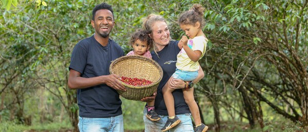 Familie mit Korb voller Kaffeekirschen im Wald
