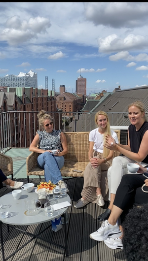 Link: Großansicht des Bildes - Bildinhalt: Gruppe trinkt Kaffee auf Dachterrasse mit Stadtblick