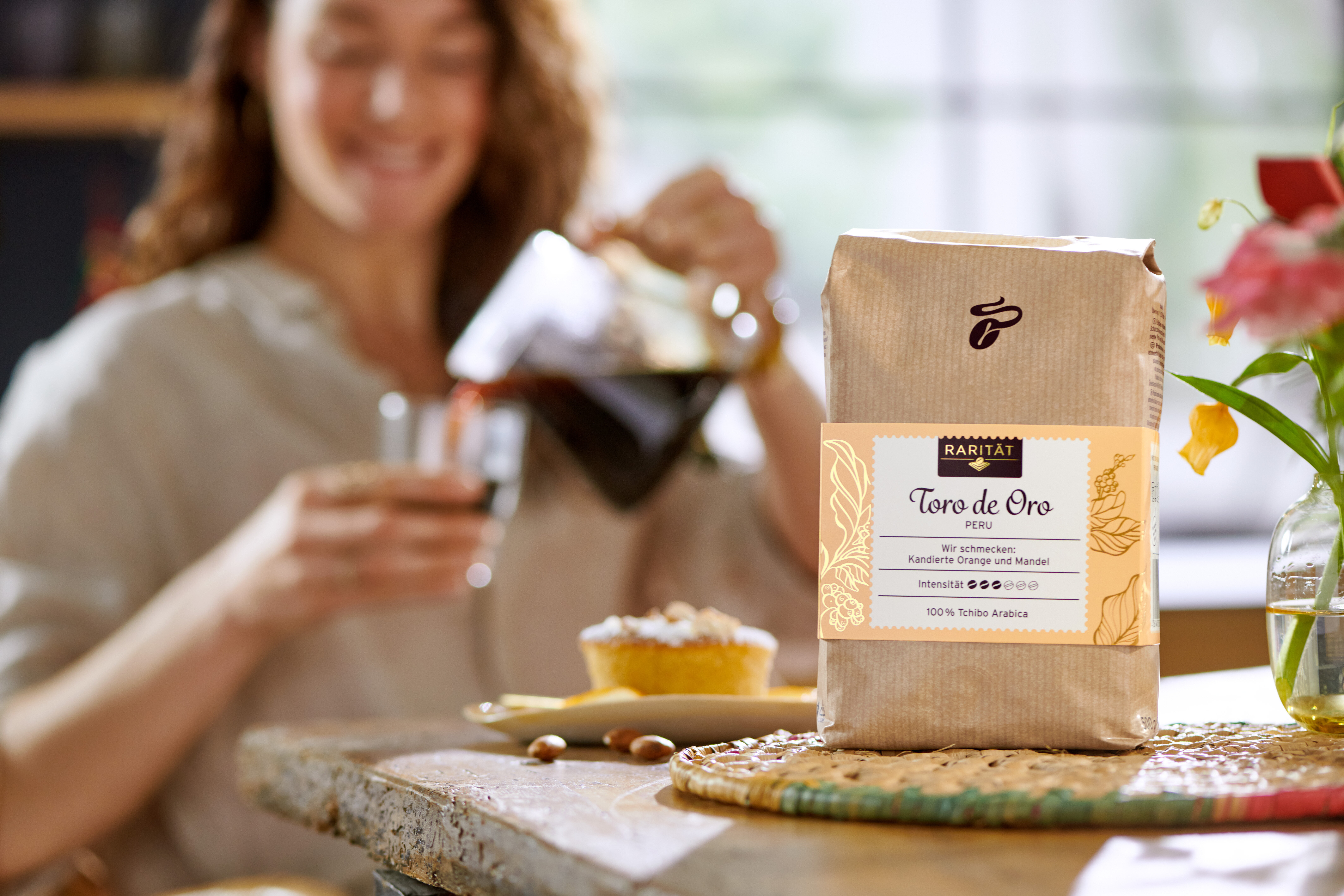 Kaffeepackung auf Tisch, Frau schenkt Kaffee ein