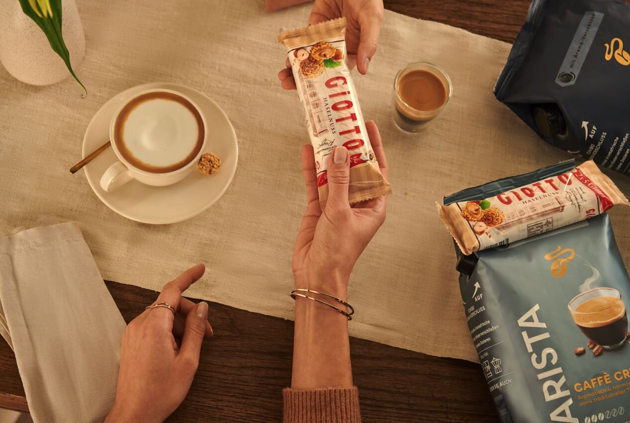 Hände reichen Giotto-Riegel bei Kaffee und Keksen