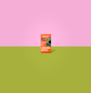 Link: Großansicht des Bildes - Bildinhalt: Orange Kaffepackung auf grünem Boden, rosa Hintergrund