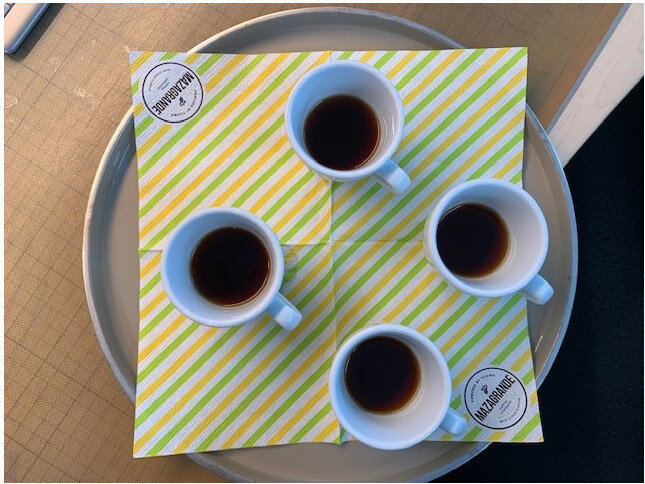 Vier Espressotassen auf gelb gestreifter Serviette