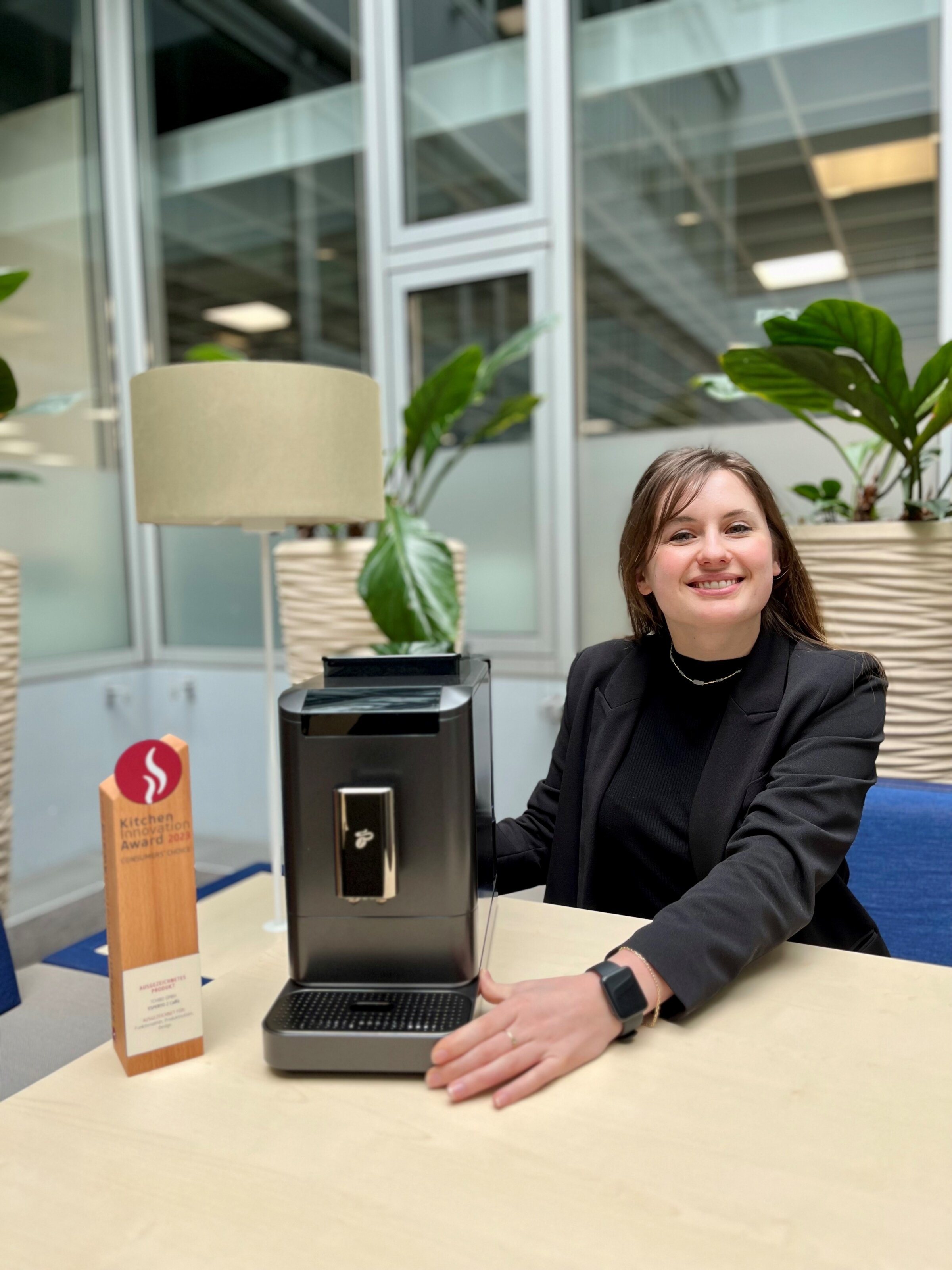 Frau präsentiert Kaffeemaschine mit Award