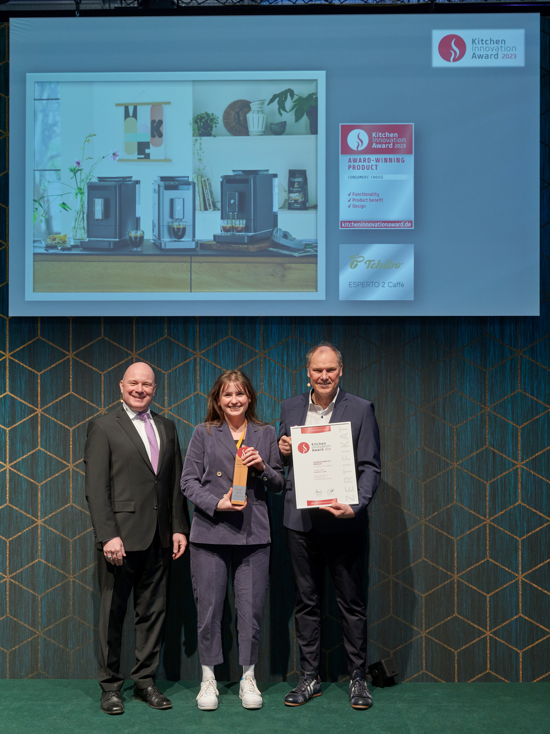Drei Personen mit Küchenpreis und Urkunde auf Bühne