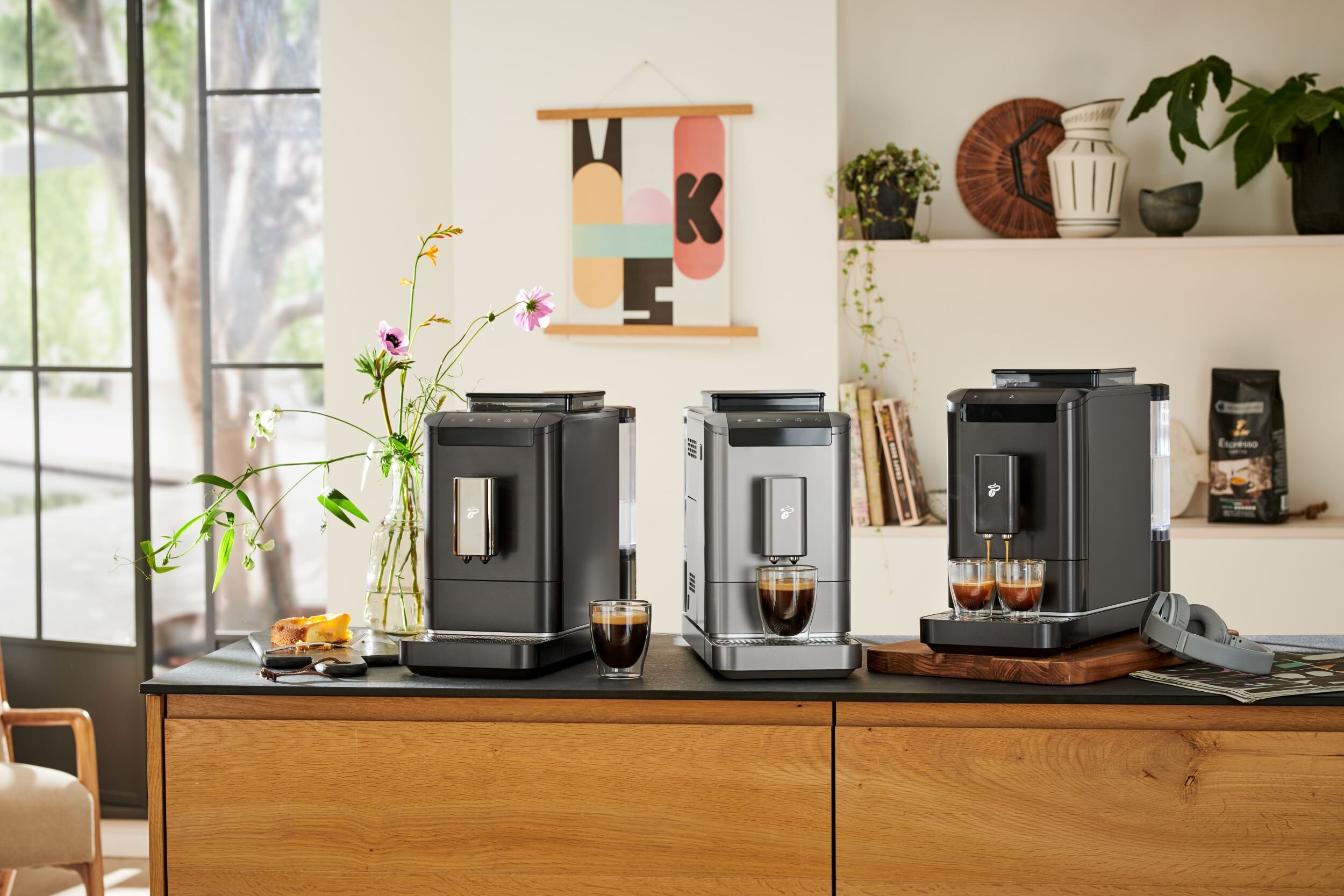 Drei moderne Kaffeevollautomaten auf Küchenzeile