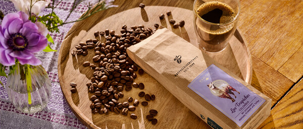 Kaffeebohnen, Kaffeetasse und Blumen auf Holzteller