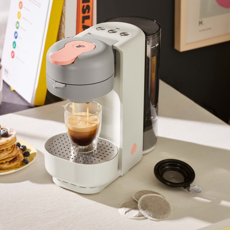 Kaffeemaschine brüht Espresso neben Pancakes