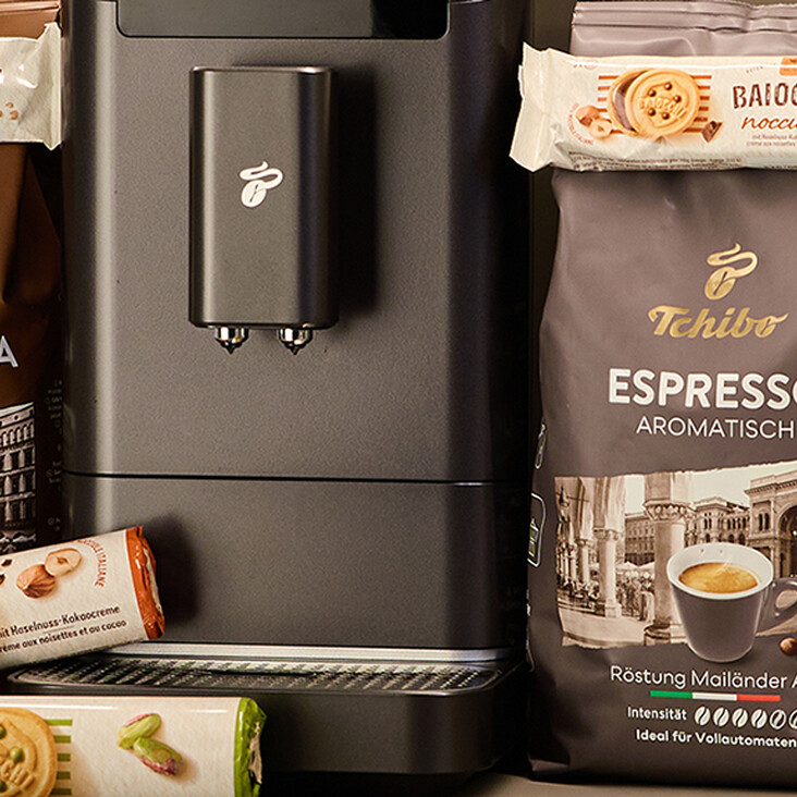 Tchibo Kaffeepackungen und Kekse neben Maschine