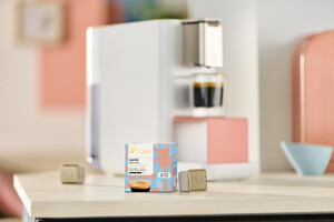 Link: Großansicht des Bildes - Bildinhalt: Kapselkaffee-Packung vor moderner Kaffeemaschine