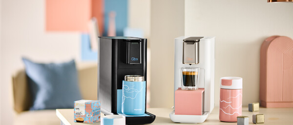 Zwei Qbo-Kaffeemaschinen mit Bechern auf Küchenzeile