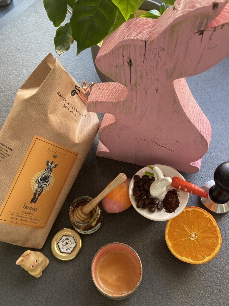 Kaffeeszene mit rosa Holzhase und Orangenscheibe