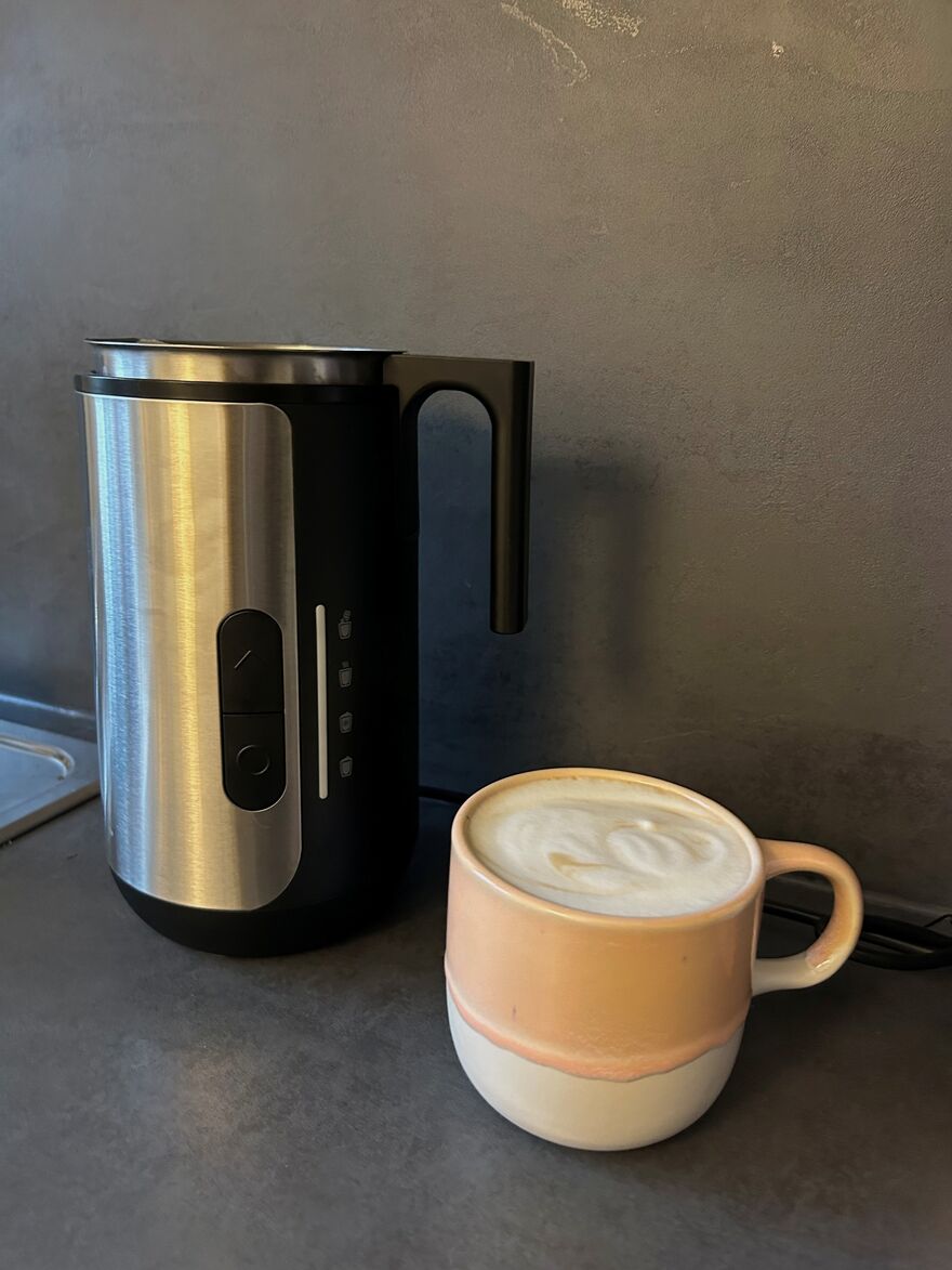 Milchaufschäumer neben Tasse Cappuccino