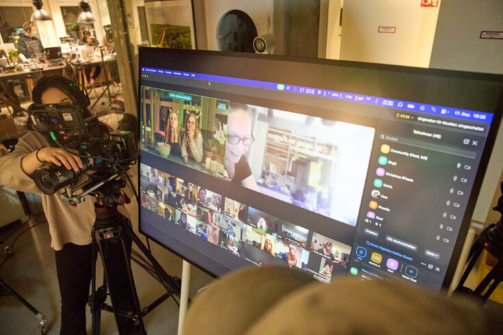Person filmt großes Display mit Videokonferenz