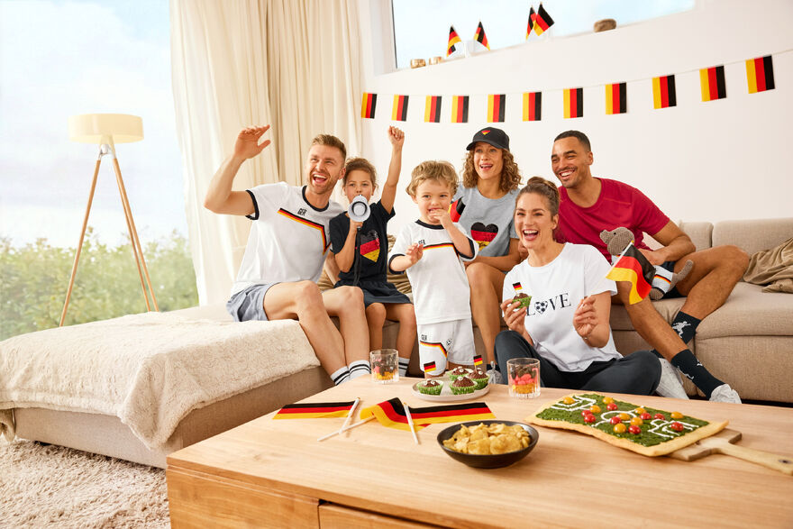 Familie feiert Fußballspiel mit Deutschlandflaggen