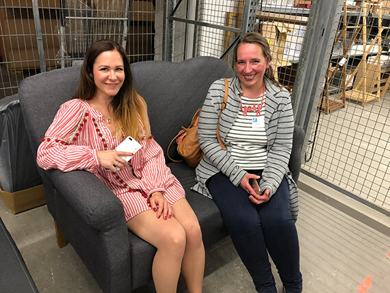 Zwei Frauen sitzen auf grauem Sofa im Lager