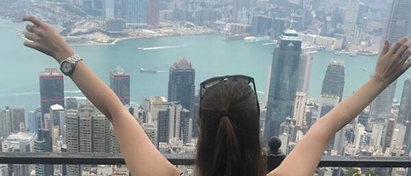 Frau mit ausgebreiteten Armen über Skyline am Hafen