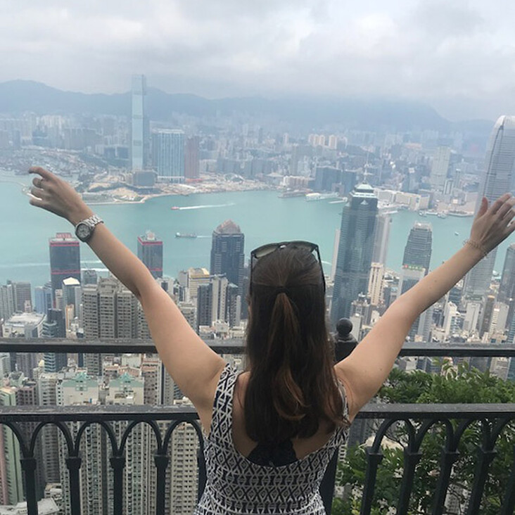 Frau mit ausgebreiteten Armen über Skyline am Hafen