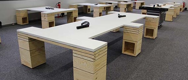 Raum mit mehreren modernen Holztischen und Steckdosen