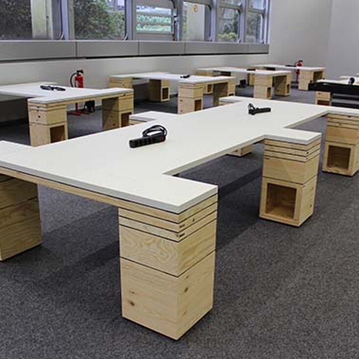 Raum mit mehreren modernen Holztischen und Steckdosen