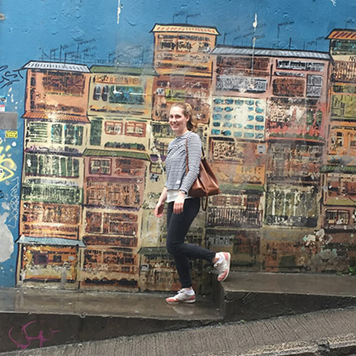 Person geht an bunter Hausfassaden-Graffitiwand vorbei