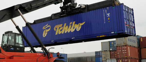 Kran hebt blauen Tchibo-Container im Hafen