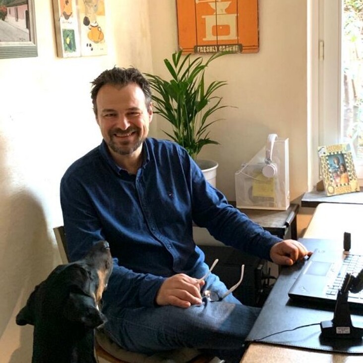 Mann im Homeoffice mit Hund neben dem Schreibtisch