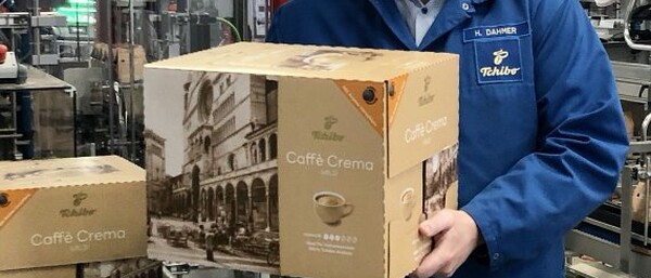 Mitarbeiter hält Caffè-Crema-Karton im Werk