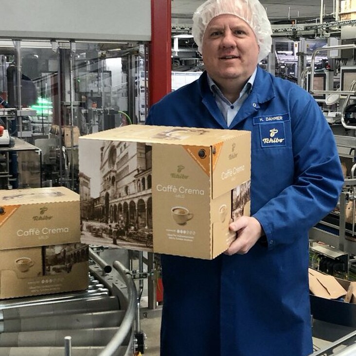 Mitarbeiter hält Caffè-Crema-Karton im Werk
