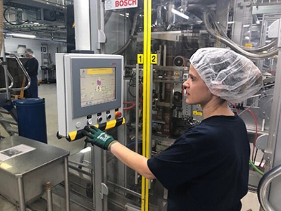 Mitarbeiterin bedient Maschinensteuerung in Fabrik