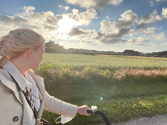 Frau radelt bei Sonnenuntergang am Feld entlang