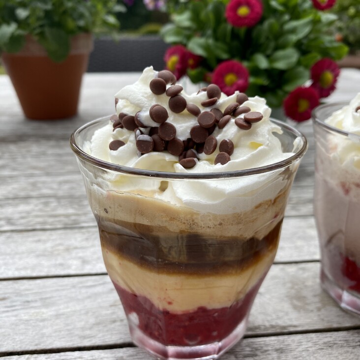 Schichtdessert mit Sahne und Schokostreuseln draußen
