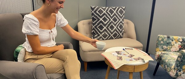 Frau im Büro-Sitzbereich mit Tasse am Beistelltisch