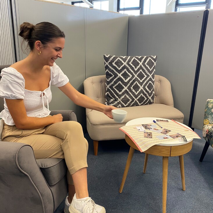 Frau im Büro-Sitzbereich mit Tasse am Beistelltisch