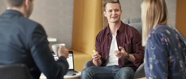 Drei Personen im Gespräch in moderner Büroecke