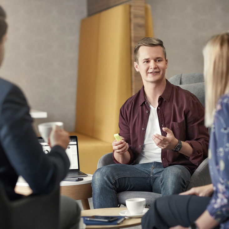 Drei Personen im Gespräch in moderner Büroecke