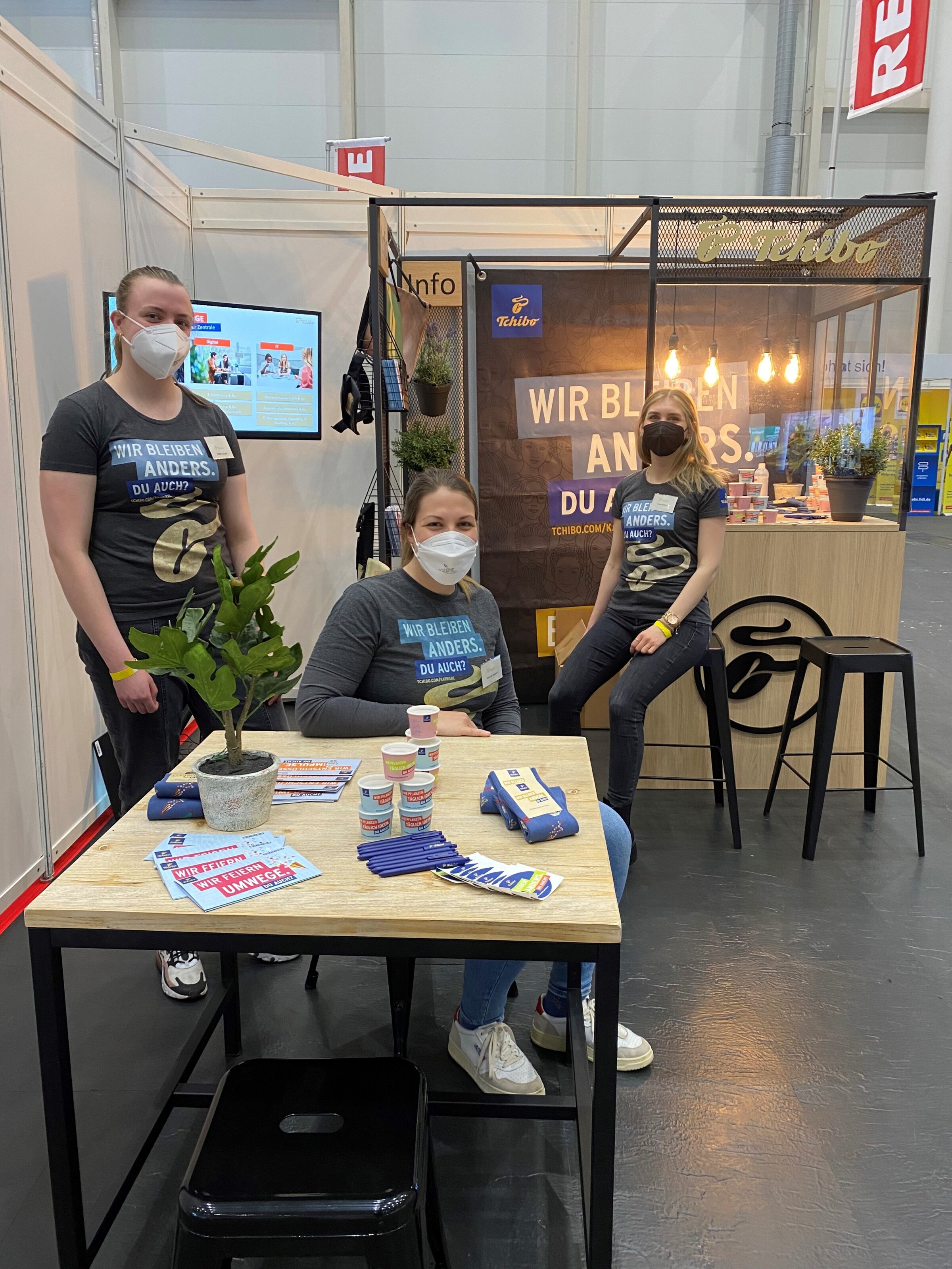 Messestand von Tchibo mit drei Mitarbeitenden