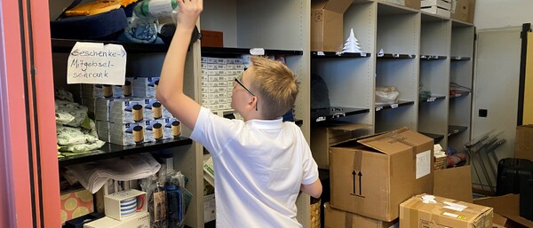 Kind in Lagerraum sortiert Kartons und Regale