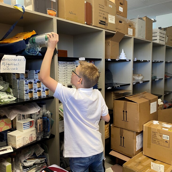 Kind in Lagerraum sortiert Kartons und Regale