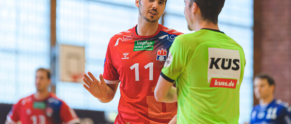 Handballspieler diskutiert mit Schiedsrichter