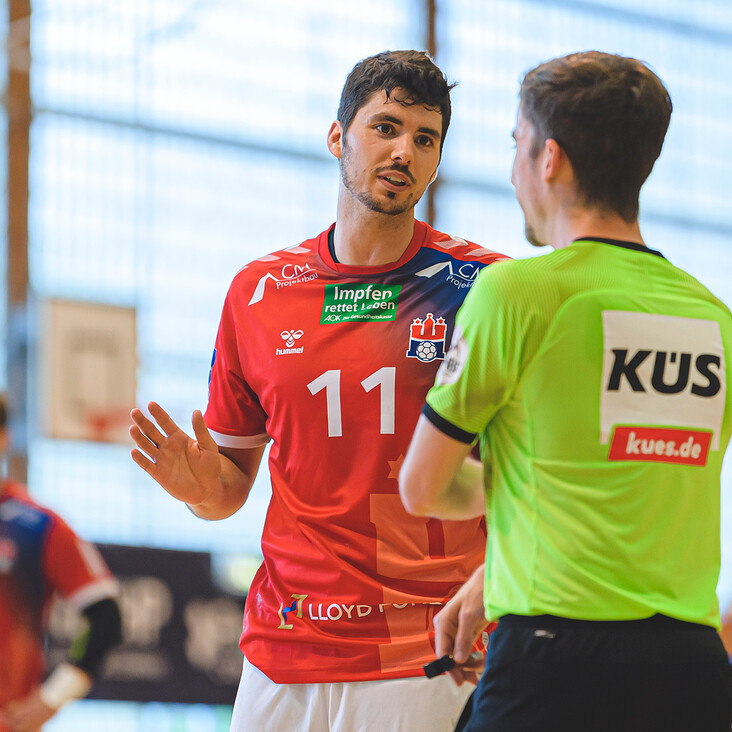 Handballspieler diskutiert mit Schiedsrichter